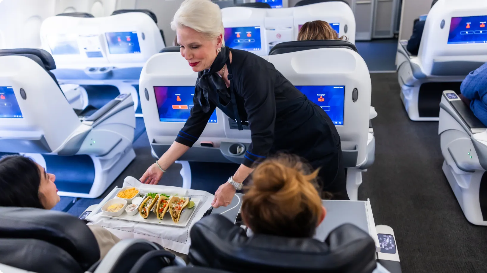 A flight attendant handing food to a passenger
